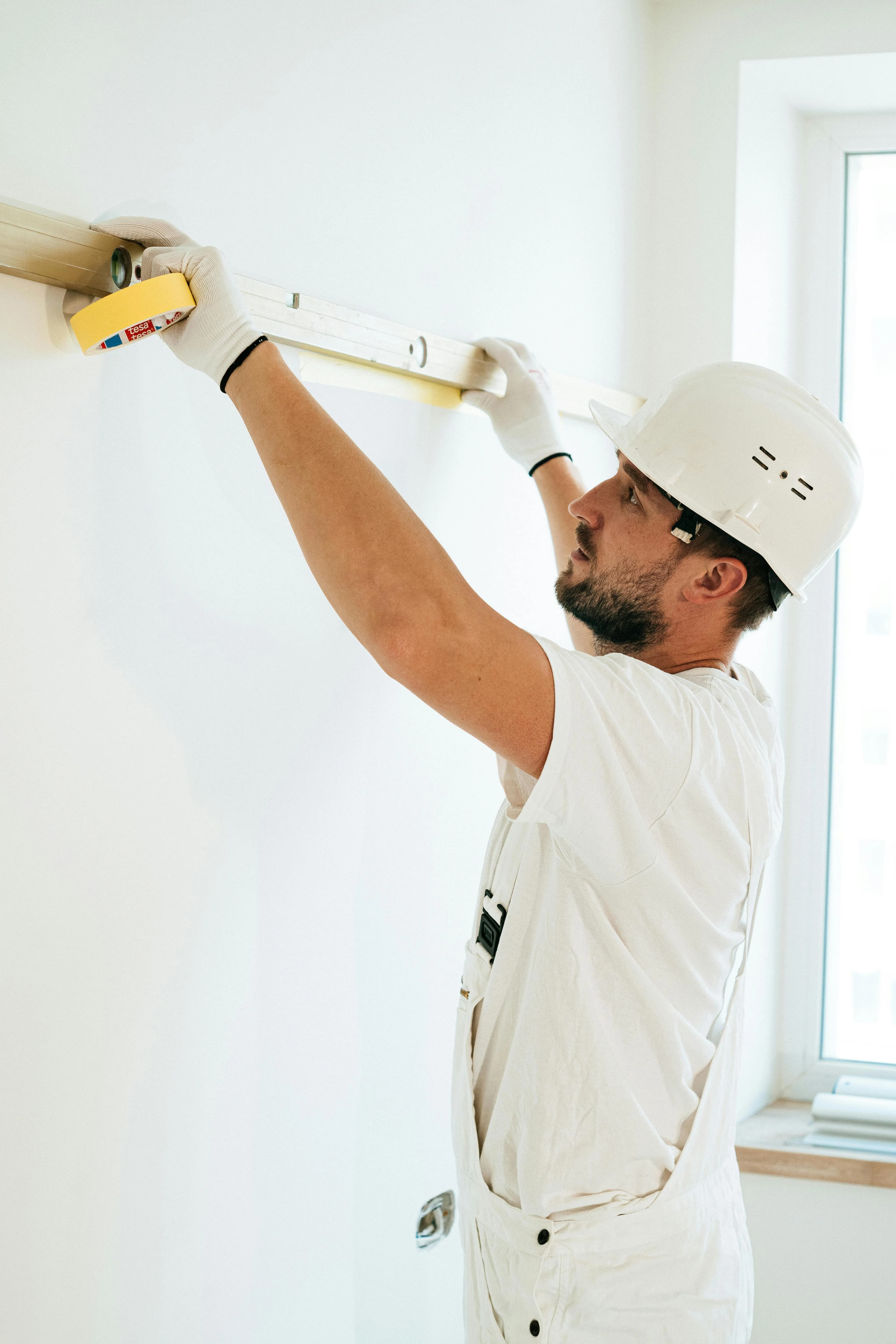 Profesional con casco usando un nivel para medir durante una reforma interior